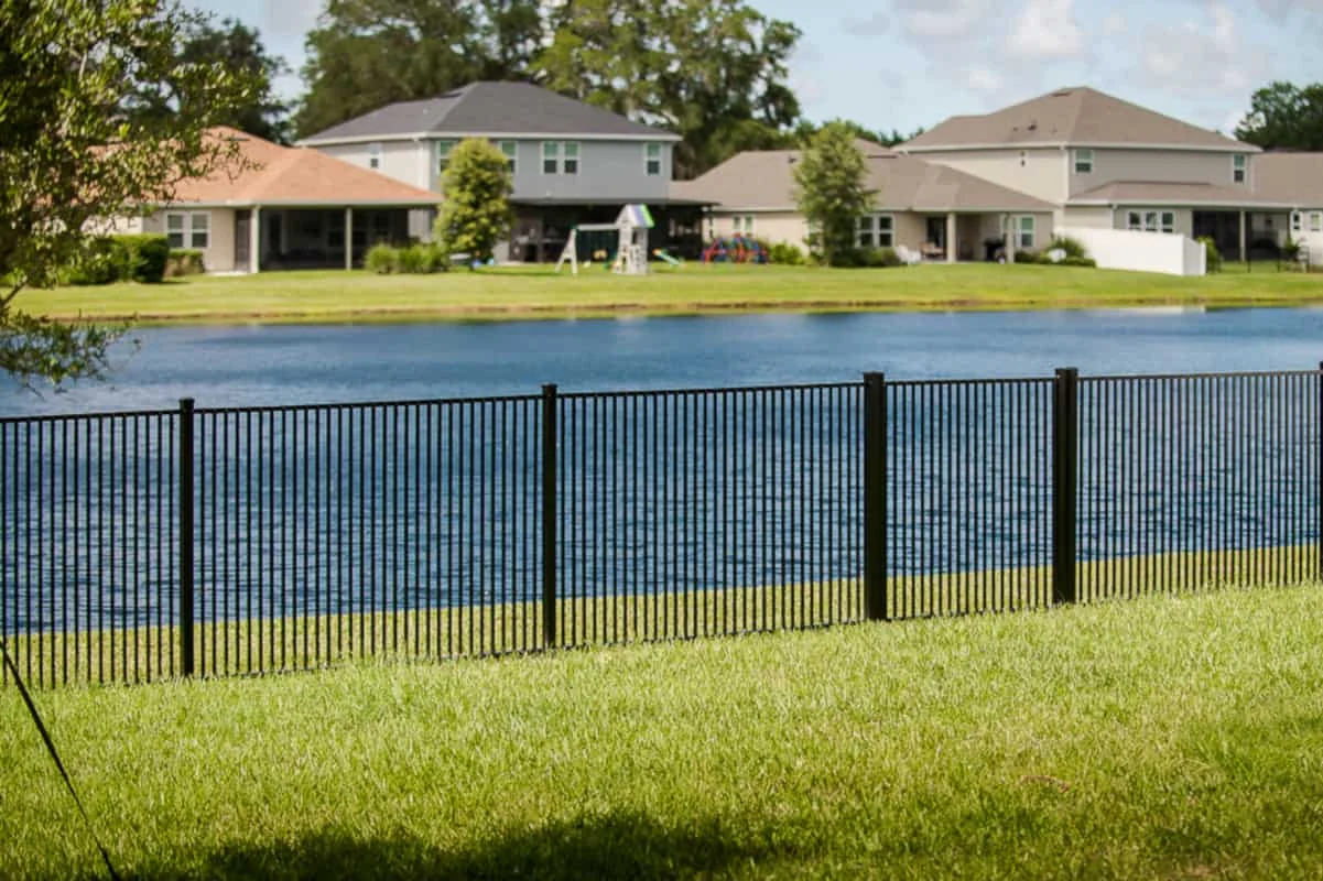 Black aluminum fence beside a lakeside residential backyard
